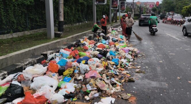 
					Petugas DLH Kota Semarang sedang menyapu muatan sampah yang berceceran di jalan | dok humas pemkot.